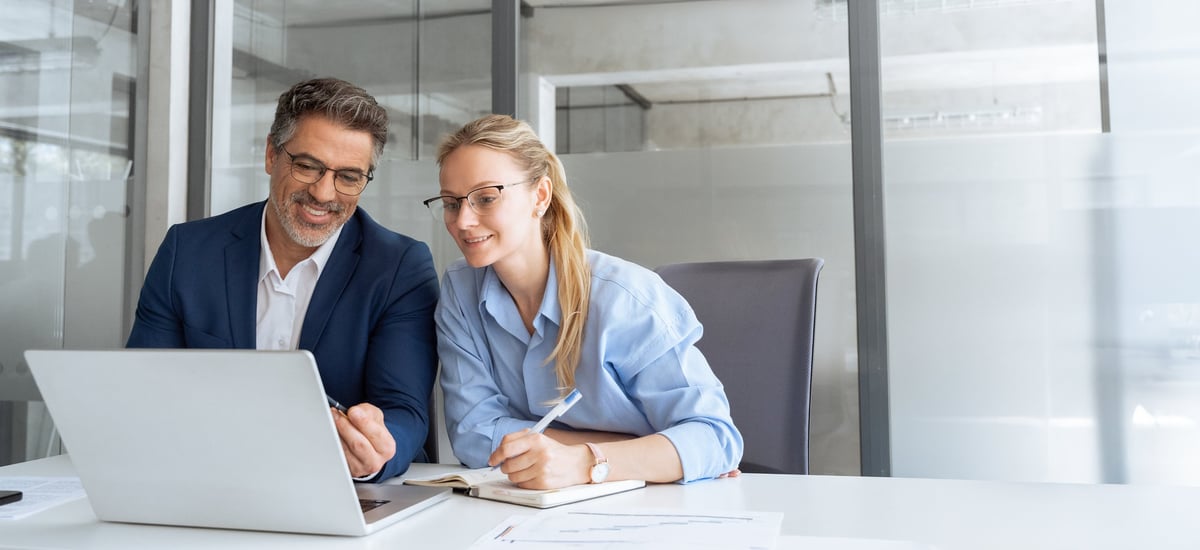 A mentor guiding a colleague through a technical project on a laptop
